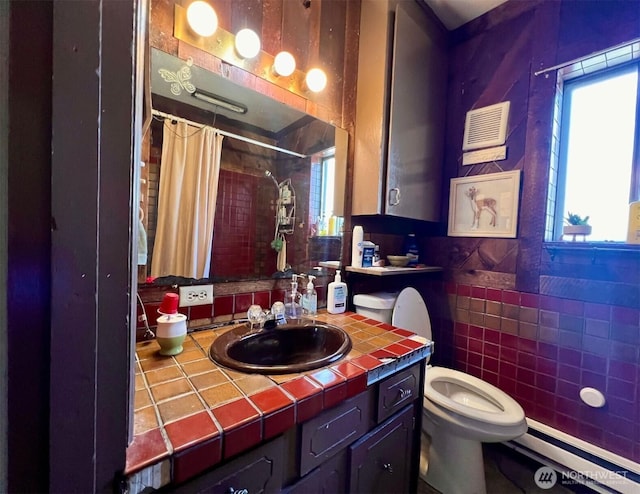 bathroom featuring a shower with shower curtain, baseboard heating, tile walls, and a wealth of natural light