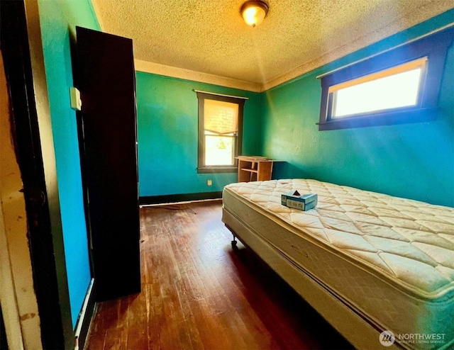 bedroom featuring baseboards, dark wood-style floors, and a textured ceiling