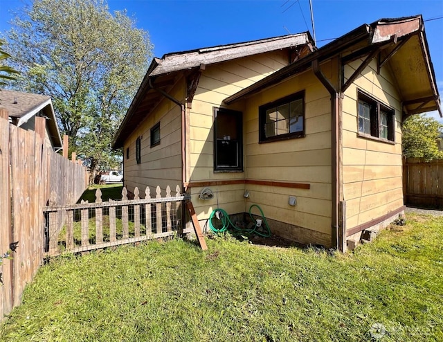 view of side of home featuring a lawn and fence