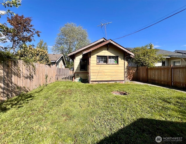 rear view of house featuring a lawn and a fenced backyard