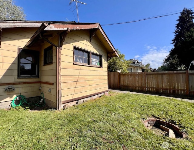 view of side of home with a lawn and fence