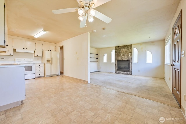 unfurnished living room with light carpet, a fireplace, baseboards, ceiling fan, and a sink
