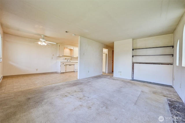 unfurnished living room with light colored carpet, a ceiling fan, and baseboards