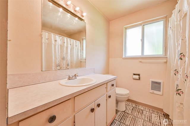 full bathroom with toilet, baseboards, heating unit, and vanity
