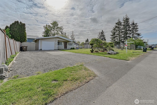 ranch-style home with a garage, fence, driveway, and a front lawn