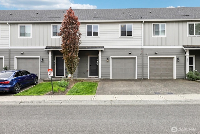 multi unit property with board and batten siding, an attached garage, and driveway