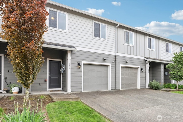 view of property with board and batten siding, driveway, and a garage