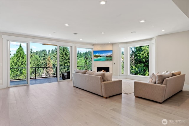 living room with a lit fireplace, light wood-style floors, and recessed lighting