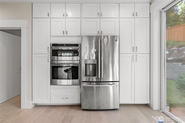 kitchen featuring stainless steel appliances, white cabinetry, and light wood finished floors