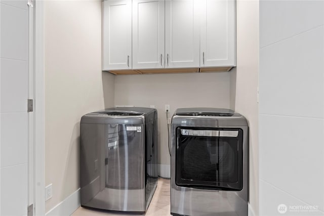 washroom with washer and dryer, cabinet space, and baseboards
