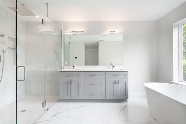 bathroom featuring marble tiled flooring, a marble finish shower, a freestanding tub, and double vanity