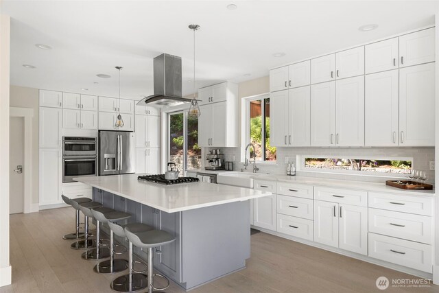 16831 84th Ln NE, Kenmore, WA 98028 - kitchen featuring appliances with stainless steel finishes, a sink, island exhaust hood, a kitchen breakfast bar, and tasteful backsplash