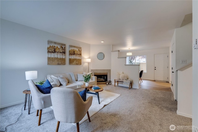 living area featuring baseboards, a fireplace, and carpet flooring