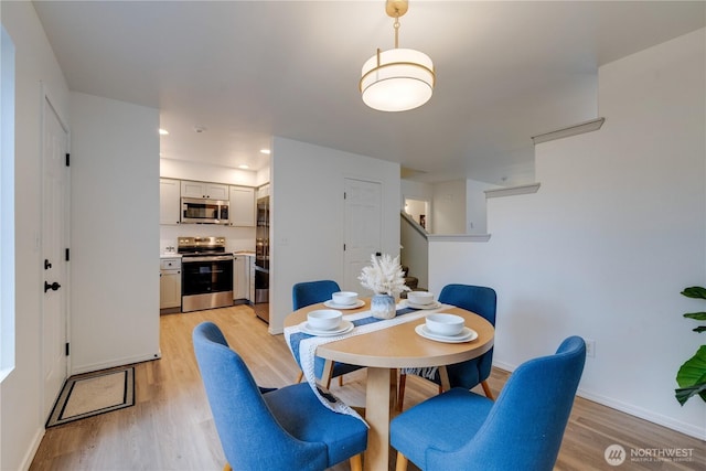 dining room with stairway, baseboards, and light wood finished floors