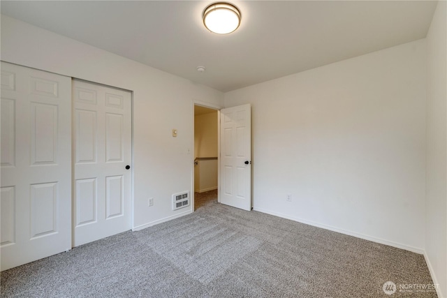unfurnished bedroom with baseboards, visible vents, carpet, and a closet
