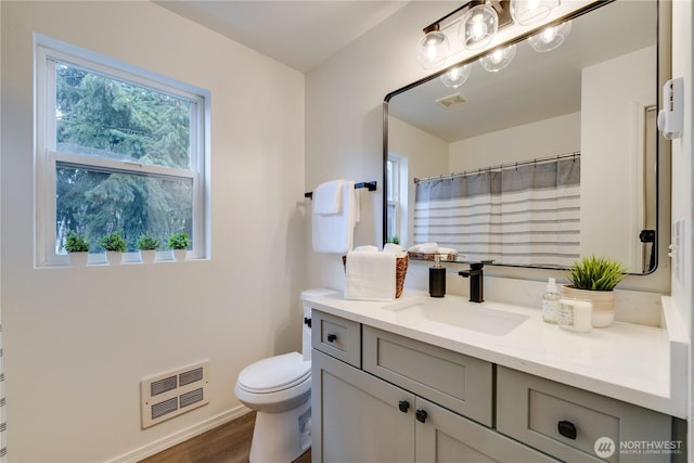 bathroom with vanity, toilet, wood finished floors, and visible vents