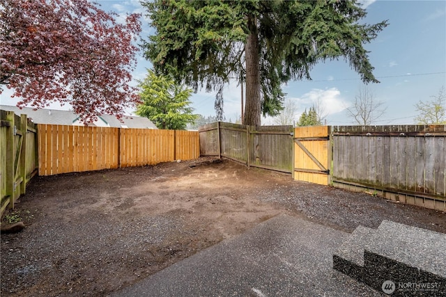view of yard with a fenced backyard and a gate