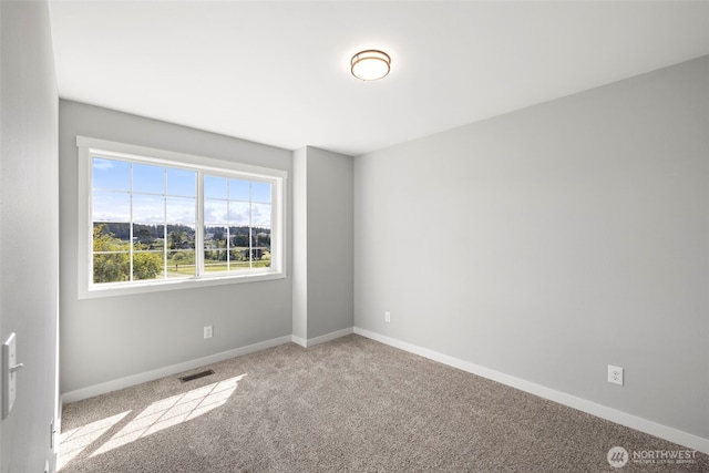 carpeted empty room featuring baseboards