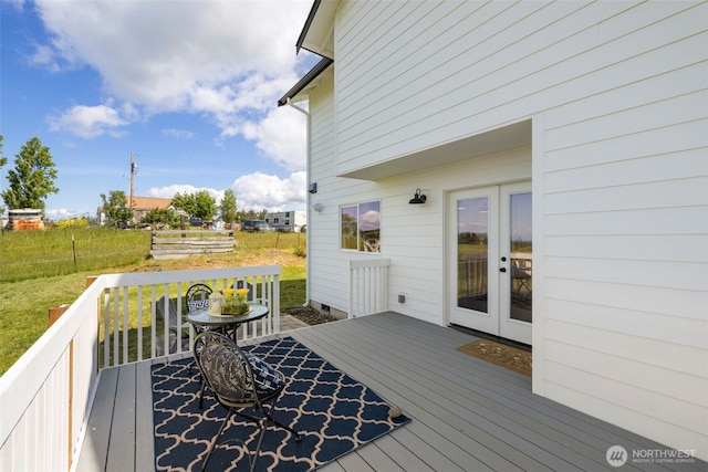 wooden terrace featuring french doors and a lawn