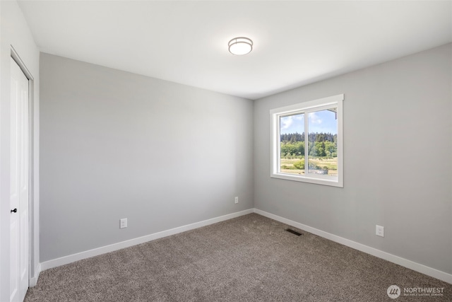 spare room featuring carpet and baseboards