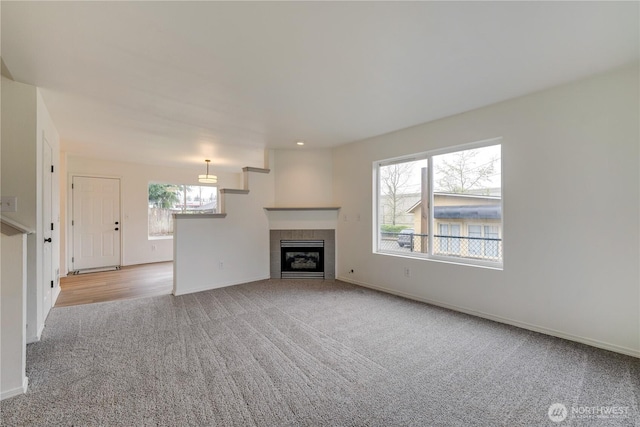 unfurnished living room with carpet floors, baseboards, and a fireplace