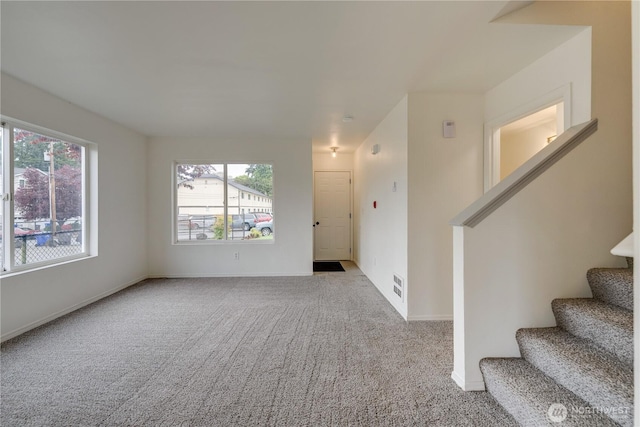 interior space with carpet flooring, baseboards, visible vents, and stairway