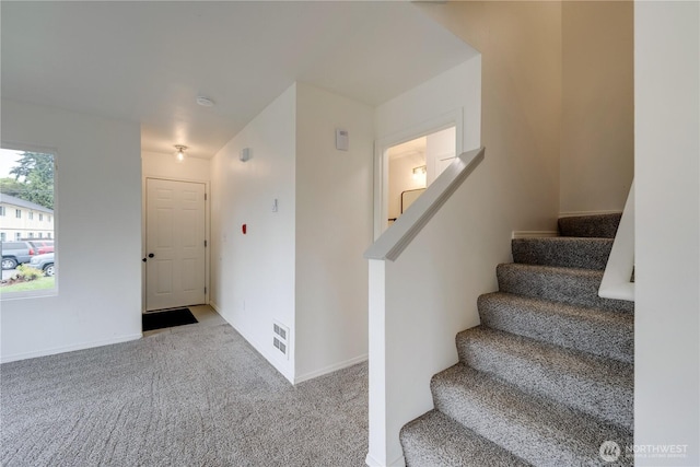 staircase featuring carpet floors, baseboards, and visible vents