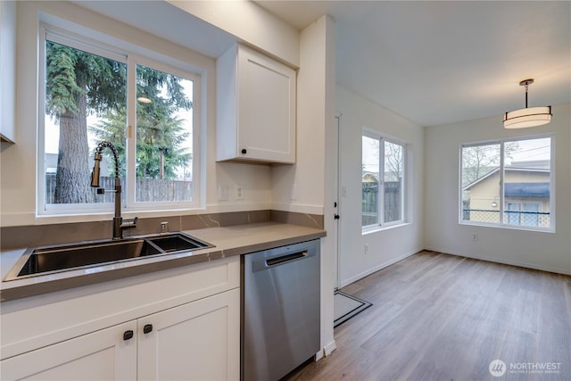 kitchen with stainless steel dishwasher, light wood-style floors, white cabinetry, a sink, and hanging light fixtures
