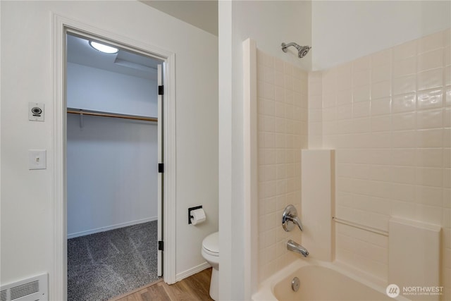 bathroom featuring visible vents, wood finished floors, bathing tub / shower combination, toilet, and a walk in closet