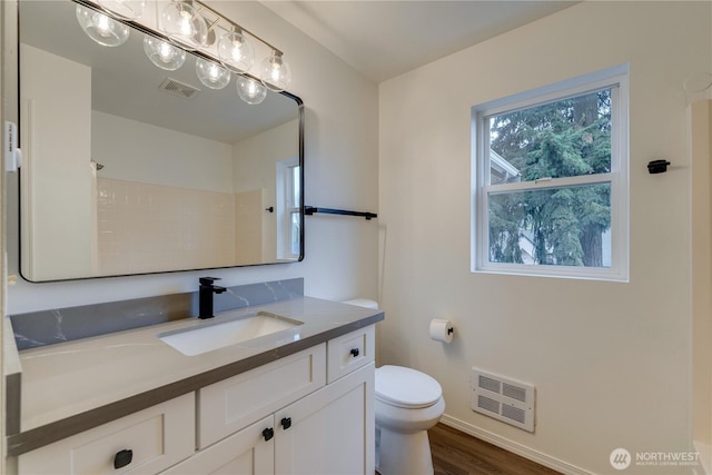 bathroom with visible vents, vanity, wood finished floors, toilet, and baseboards