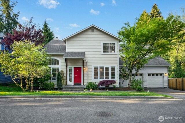 traditional-style home with fence, driveway, a shingled roof, and a garage