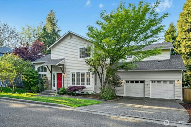 traditional-style house with concrete driveway, roof with shingles, and a garage