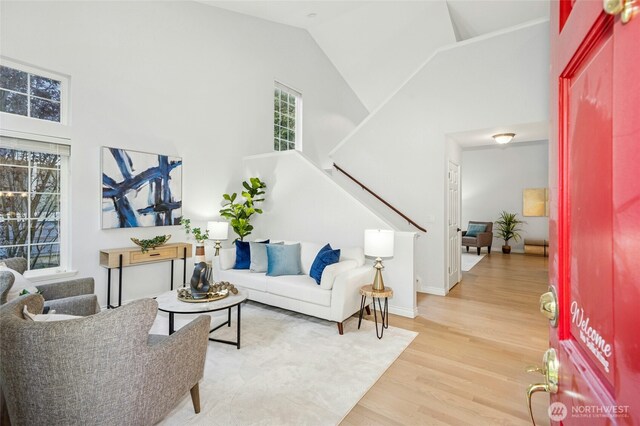 living area with baseboards, stairs, wood finished floors, and high vaulted ceiling