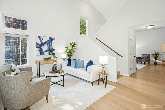 living room featuring baseboards, stairs, wood finished floors, and high vaulted ceiling