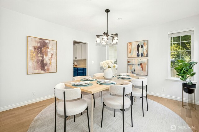 dining area with light wood-style floors, baseboards, and a notable chandelier
