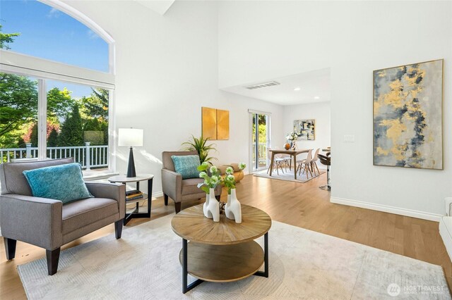 sitting room featuring baseboards, a high ceiling, visible vents, and wood finished floors