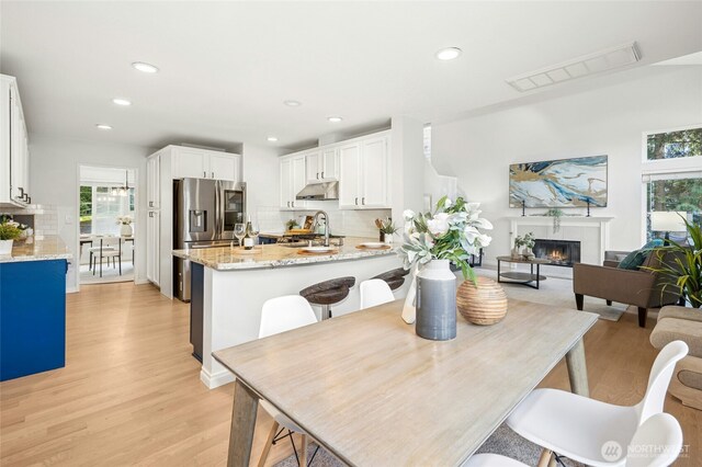 dining space with recessed lighting, visible vents, a glass covered fireplace, and light wood finished floors