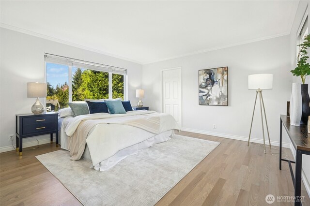 bedroom featuring crown molding, light wood-style flooring, and baseboards