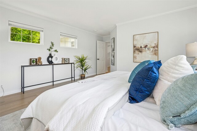 bedroom featuring baseboards, ornamental molding, and wood finished floors