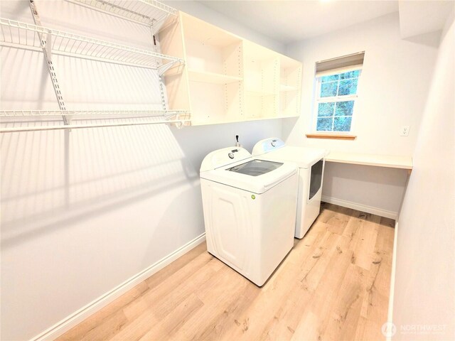 washroom featuring washing machine and clothes dryer, laundry area, baseboards, and light wood-style flooring