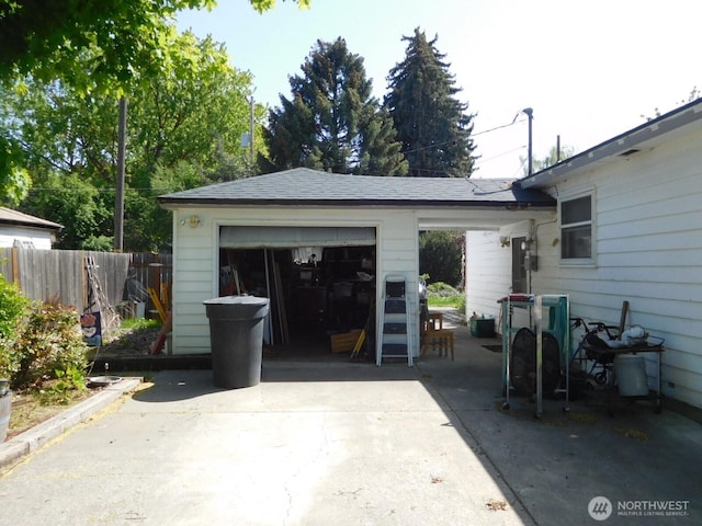 garage featuring fence and concrete driveway
