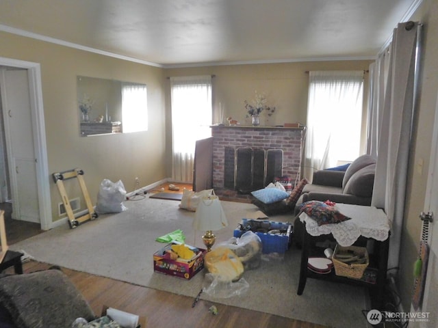 living area featuring baseboards, ornamental molding, a fireplace, and wood finished floors