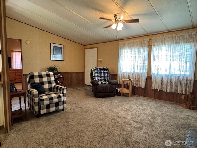 sitting room featuring lofted ceiling, ceiling fan, wooden walls, a wainscoted wall, and carpet