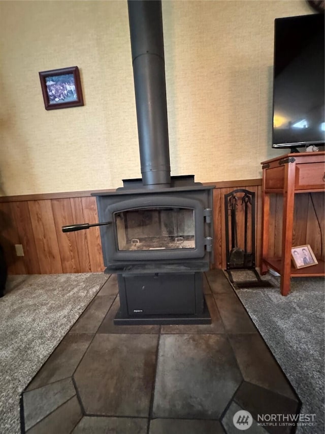 room details featuring wood walls, wainscoting, and a wood stove