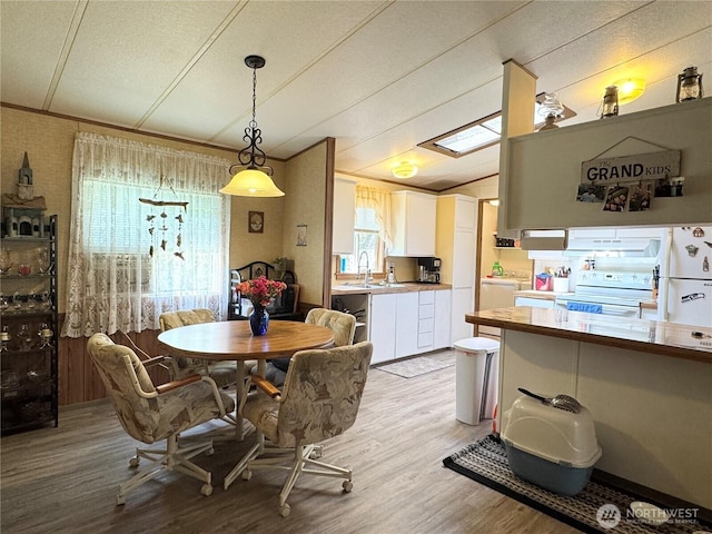 dining room with washer / clothes dryer, a textured ceiling, vaulted ceiling, and light wood-style floors