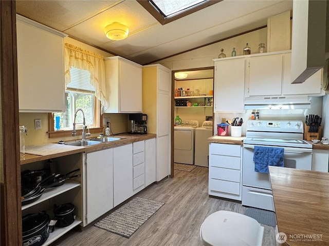 kitchen with electric range, a sink, vaulted ceiling with skylight, under cabinet range hood, and washer and clothes dryer