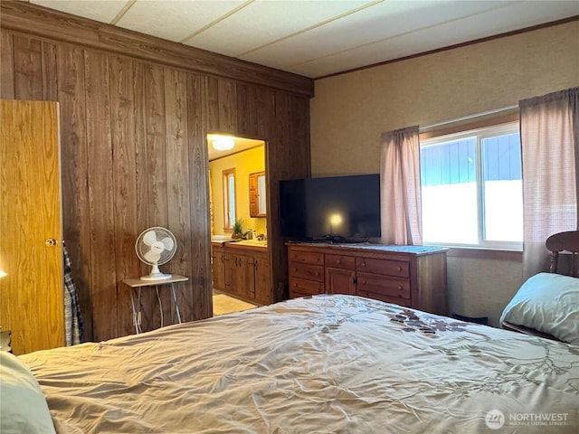 bedroom featuring wood walls and ensuite bathroom