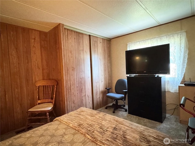 carpeted bedroom featuring wood walls