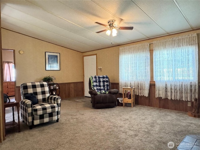 sitting room featuring ceiling fan, wainscoting, carpet floors, lofted ceiling, and wooden walls