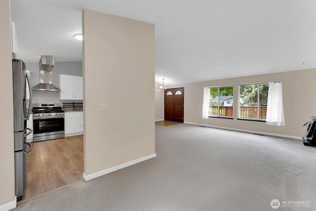 unfurnished living room featuring light carpet and baseboards